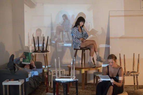 Drei Personen lesen in einem Atelier mit projizierten Bildern an der Wand